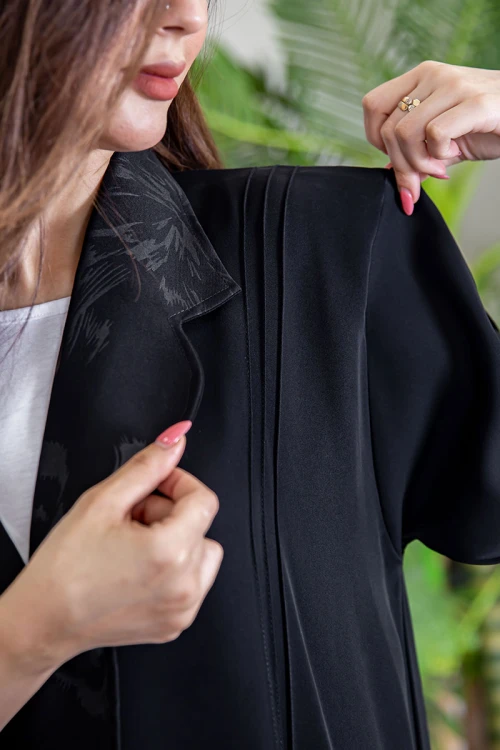 عباية نسائية أنيقة لون أسود ياقة مطوية مزينة بنقوش في الياقة و أطراف الأكمام بأزرار من الأمام مع طرحة