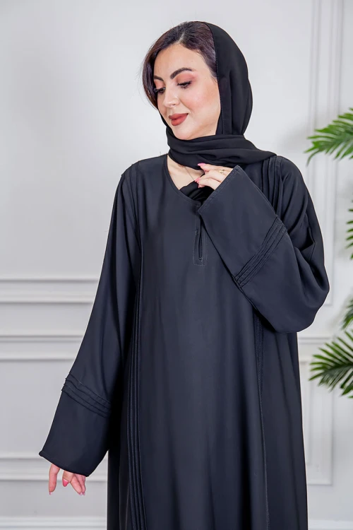 عباية نسائية أنيقة لون أسود ياقة دائرية بأزرار مزينة بطيات طويلة مغلقة من الأمام مع طرحة