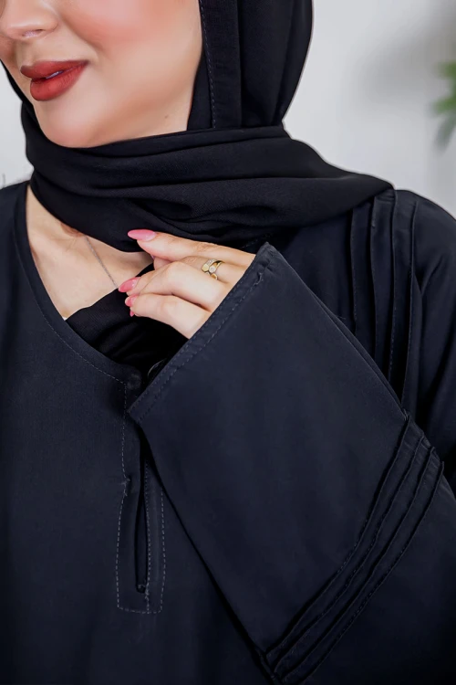 عباية نسائية أنيقة لون أسود ياقة دائرية بأزرار مزينة بطيات طويلة مغلقة من الأمام مع طرحة