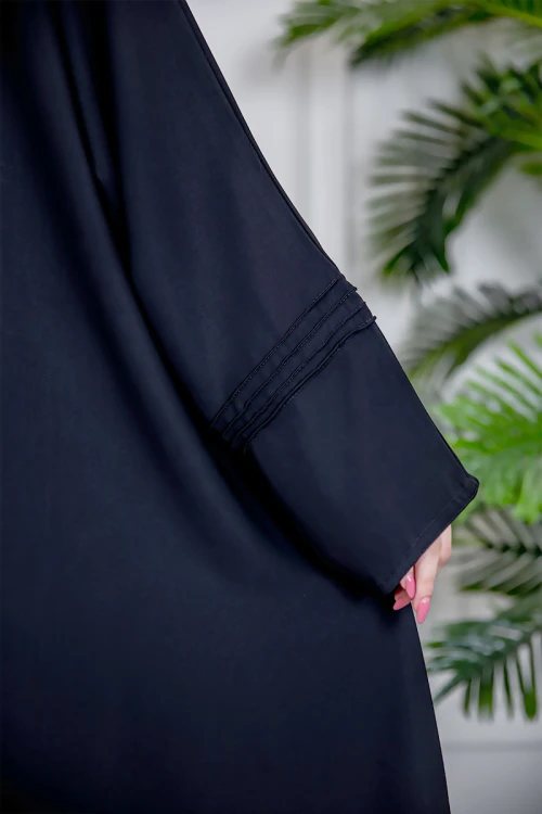 عباية نسائية أنيقة لون أسود ياقة دائرية بأزرار مزينة بطيات طويلة مغلقة من الأمام مع طرحة