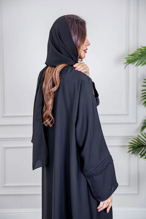 عباية نسائية أنيقة لون أسود ياقة دائرية بأزرار مزينة بطيات طويلة مغلقة من الأمام مع طرحة