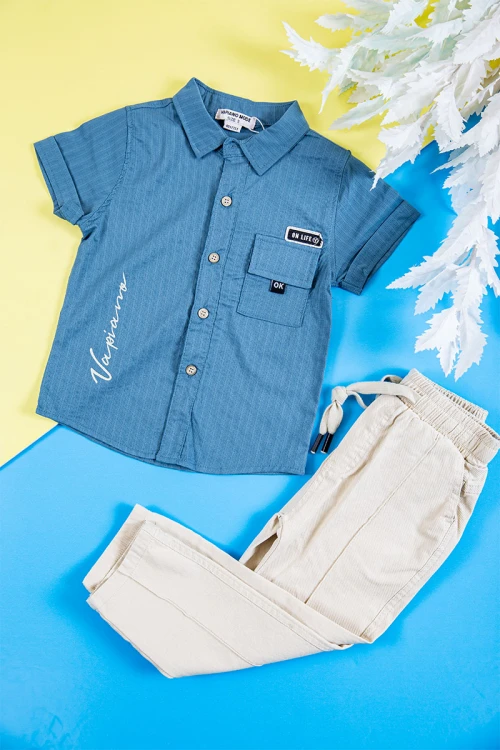 طقم ولادي قطعتين قميص لون سماوي بكتابات و طبعات و أزرار و جيب من الأمام و بنطلون طويل لون بيج فاتح برباط في الخصر و جيوب من الجانبين و الخلف