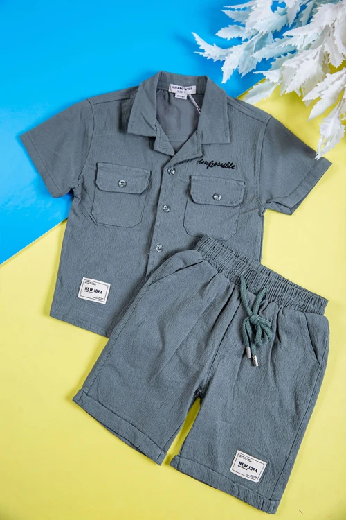 طقم ولادي قطعتين لون رصاصي قميص بكتابات و طبعات وجيوب وازرار من الأمام و شورت برباط في الخصر و جيوب من الجانبين و الخلف