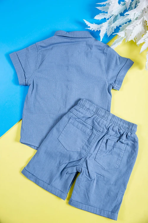 طقم ولادي قطعتين لون سماوي قميص بكتابات و طبعات وجيب وازرار من الأمام و شورت برباط في الخصر و جيوب من الجانبين و الخلف
