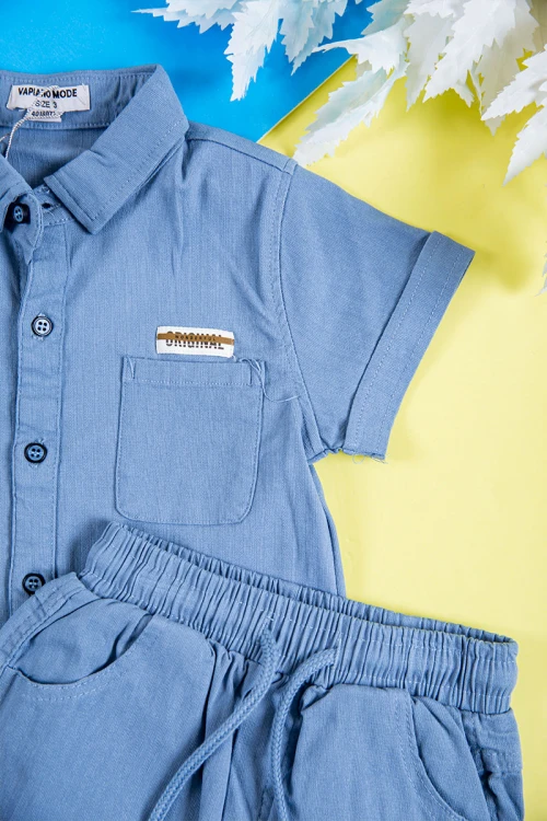 طقم ولادي قطعتين لون سماوي قميص بكتابات و طبعات وجيب وازرار من الأمام و شورت برباط في الخصر و جيوب من الجانبين و الخلف