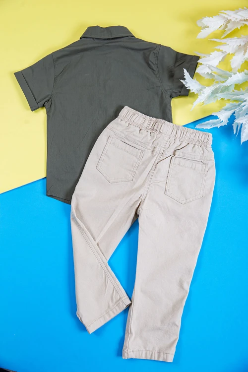 طقم ولادي قطعتين قميص لون زيتي بكتابات و طبعات و أزرار و جيب من الأمام و بنطلون طويل لون بيج فاتح برباط في الخصر و جيوب من الجانبين و الخلف