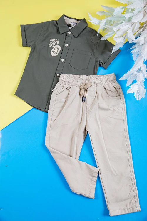 طقم ولادي قطعتين قميص لون زيتي بكتابات و طبعات و أزرار و جيب من الأمام و بنطلون طويل لون بيج فاتح برباط في الخصر و جيوب من الجانبين و الخلف