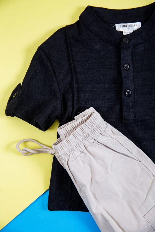 طقم ولادي قطعتين بلوزة لون أسود بطبعات و أزرار من الأمام و الأكمام و بنطلون طويل لون بيج فاتح برباط في الخصر و جيوب و سحاب من الجانبين