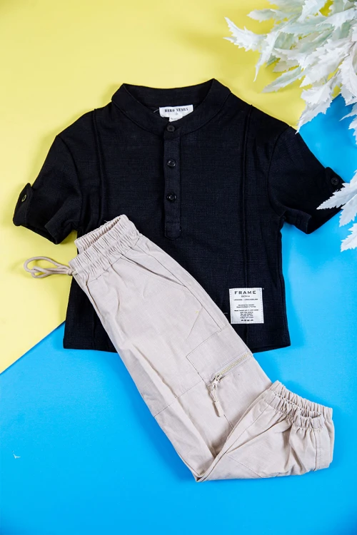 طقم ولادي قطعتين بلوزة لون أسود بطبعات و أزرار من الأمام و الأكمام و بنطلون طويل لون بيج فاتح برباط في الخصر و جيوب و سحاب من الجانبين