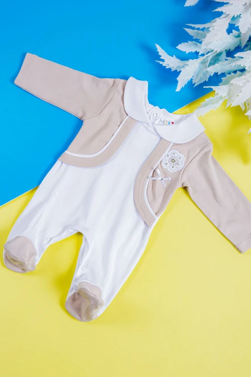 بربتوز أطفال لون بيج و أبيض مزين بفيونكة و طبعات من الأمام ذو أكمام طويلة و أزرار من الخلف و الأسفل