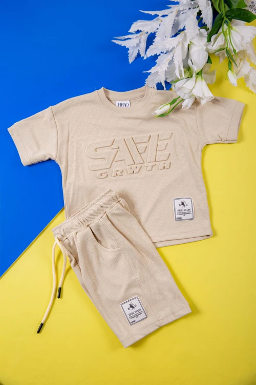 طقم ولادي قطعتين لون بيج تيشيرت بكتابات و طبعات من الأمام و شورت برباط في الخصر و جيوب من الجانبين