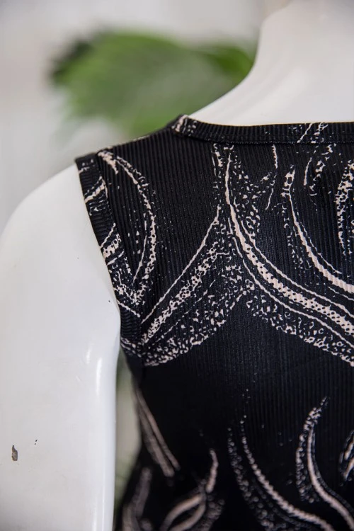 قميص نسائي قصير لون أسود مزين برسومات باللون البيج ياقة دائرية و بدون أكمام