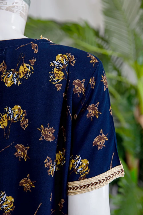 قميص نسائي طويل لون كحلي مزين برسومات ملونة و بكلفة مطرزة باللون الذهبي في الياقة و الأكمام