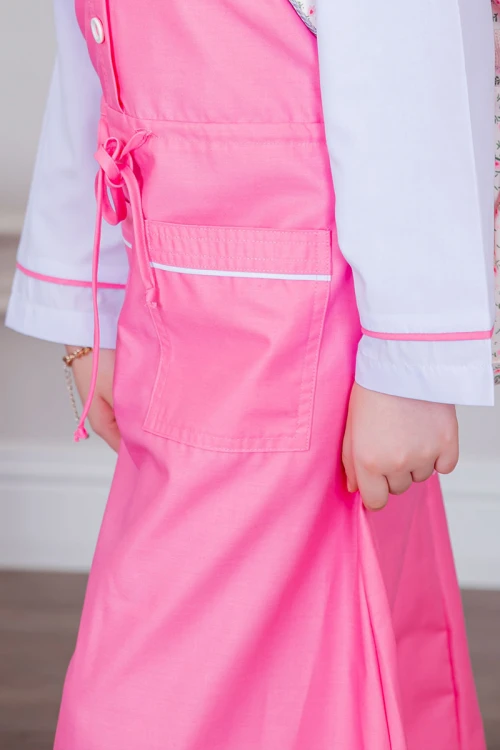 مريول بناتي مدرسي لون وردي مع قميص أبيض متصل بأزرار و جيوب من الأمام و رباط في الخصر