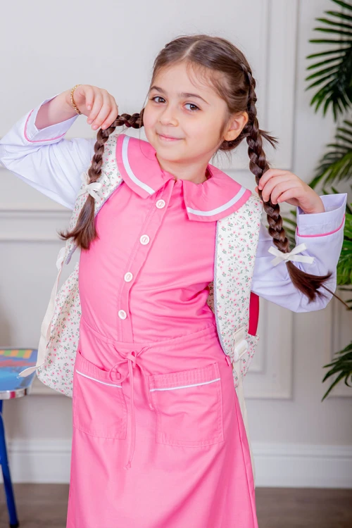 مريول بناتي مدرسي لون وردي مع قميص أبيض متصل بأزرار و جيوب من الأمام و رباط في الخصر