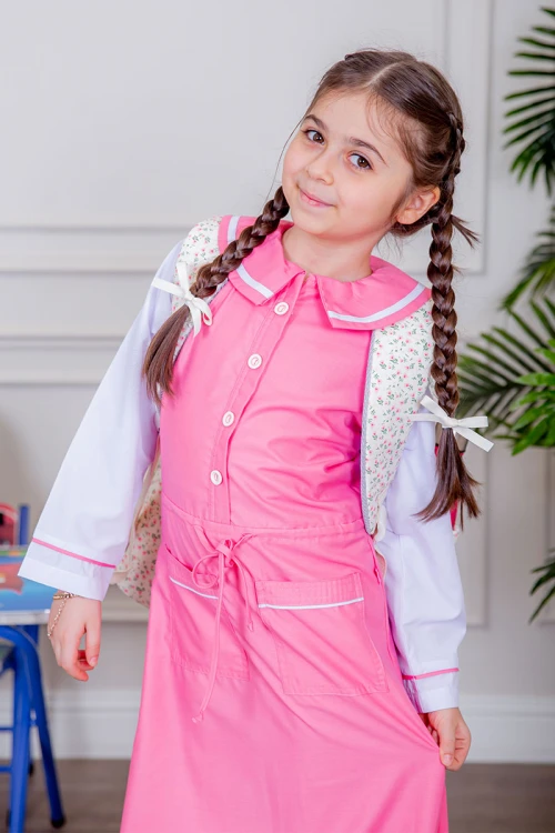 مريول بناتي مدرسي لون وردي مع قميص أبيض متصل بأزرار و جيوب من الأمام و رباط في الخصر