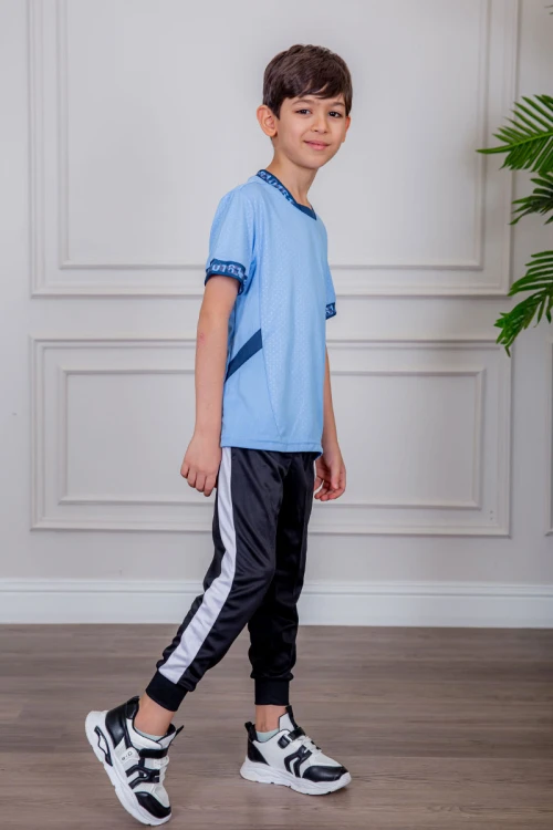 طقم ولادي رياضي قطعتين تيشيرت لون سماوي مقلم باللون الذهبي و بنطلون طويل لون أسود مخطط باللون الأحمر من الجانبين و بزم من الأسفل