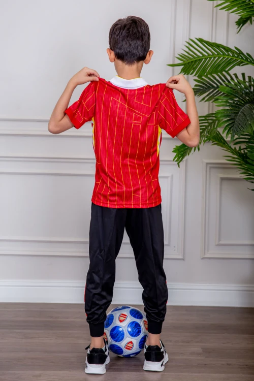 طقم ولادي رياضي قطعتين تيشيرت لون أحمر مقلم باللون الذهبي و بنطلون طويل لون أسود مخطط باللون الأحمر من الجانبين و بزم من الأسفل