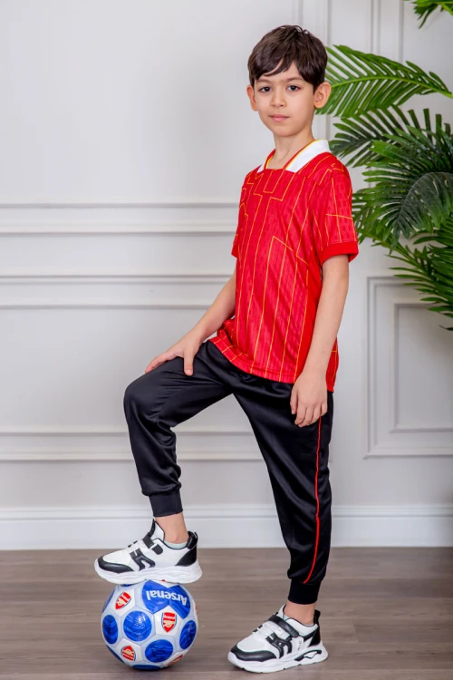طقم ولادي رياضي قطعتين تيشيرت لون أحمر مقلم باللون الذهبي و بنطلون طويل لون أسود مخطط باللون الأحمر من الجانبين و بزم من الأسفل