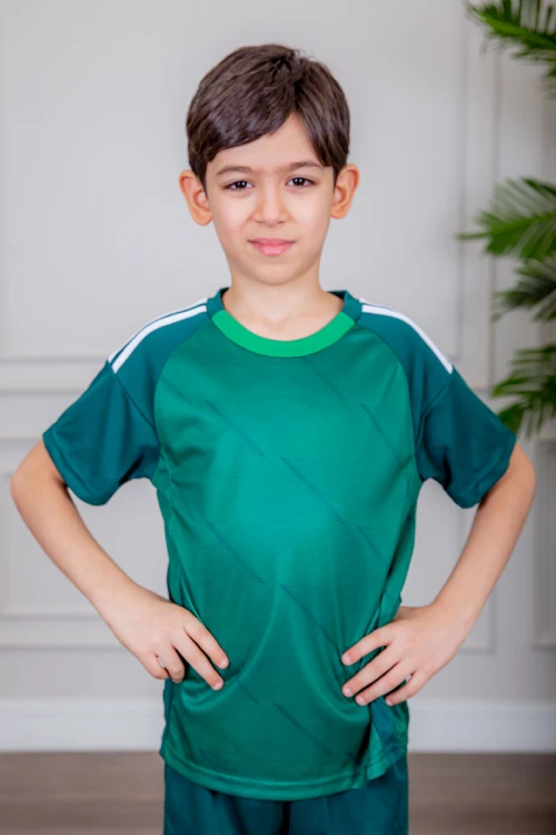 طقم ولادي رياضي قطعتين تيشيرت لون أخضر بياقة دائرية و أكتاف مخططة باللون الأبيض و شورت لون أخضر