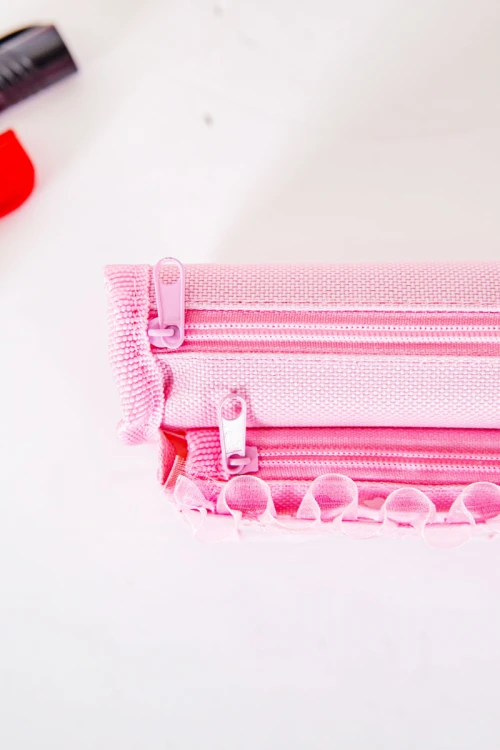 مقلمة مدرسية بناتي لون وردي مزينة بكتابات و رسومات كرتونية من الأمام و بجيوب متعددة