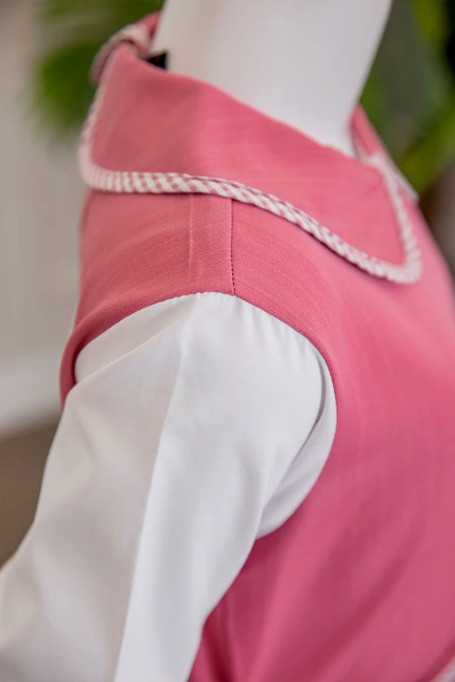 مريول بناتي مدرسي لون وردي مع قميص أبيض متصل بياقة مطوية و جيوب من الأمام و سحاب و رباط في الخلف