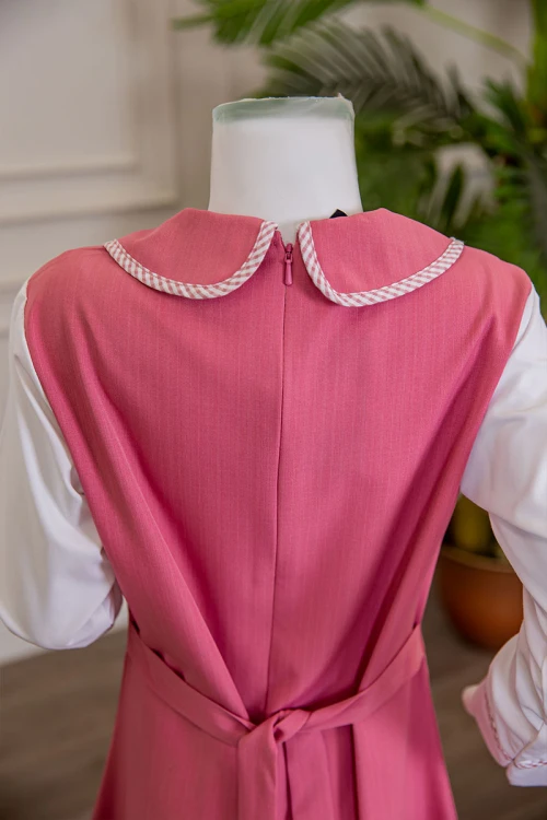 مريول بناتي مدرسي لون وردي مع قميص أبيض متصل بياقة مطوية و جيوب من الأمام و سحاب و رباط في الخلف