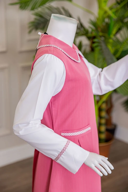 مريول بناتي مدرسي لون وردي مع قميص أبيض متصل بياقة مطوية و جيوب من الأمام و سحاب و رباط في الخلف