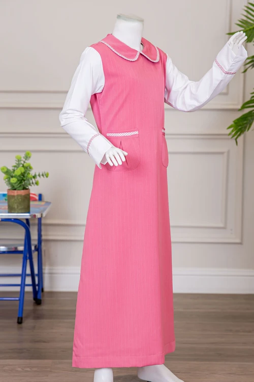 مريول بناتي مدرسي لون وردي مع قميص أبيض متصل بياقة مطوية و جيوب من الأمام و سحاب و رباط في الخلف