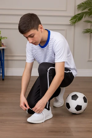 طقم ولادي رياضي قطعتين تيشيرت لون أبيض مقلم باللون الرمادي ياقة باللون الأزرق و بنطلون طويل لون أسود مخطط باللون الأبيض من الجانبين و بزم من الأسفل