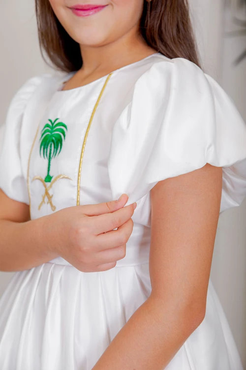 فستان بناتي لليوم الوطني لون أبيض مزين بتطريز تراثي بياقة دائرية و أكمام قصيرة و رباط في الخصر