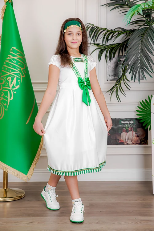 فستان بناتي لون أبيض مزين بتطريز اليوم الوطني ياقة دائرية بأكمام قصيرة و فيونكة من الأمام و رباط من الخلف