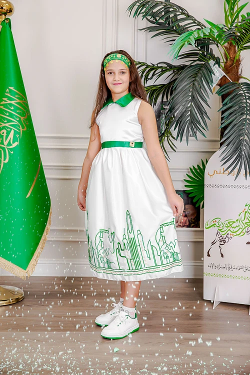 فستان بناتي لون أبيض مزين بتطريز اليوم الوطني ياقة مطوية و رباط في الخصر باللون الأخضر بدون أكمام