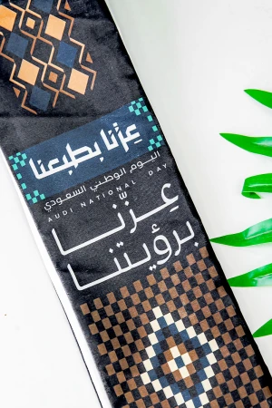 وشاح لون أسود لليوم الوطني بشعار عزنا بطبعنا