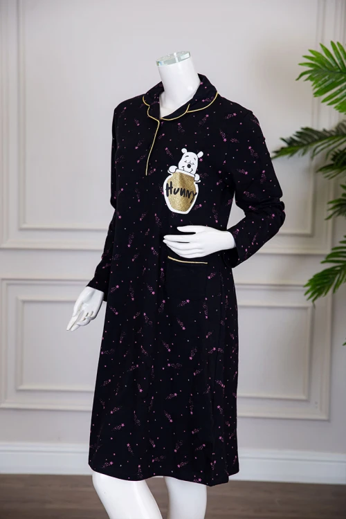 قميص نسائي شتوي ميدي لون أسود مزين بنجوم وردية و بكتابات رسومات و جيب من الأمام ياقة مطوية بأزرار و بأكمام طويلة