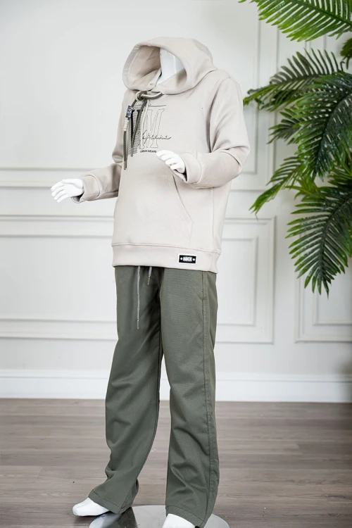 طقم قطعتين ولادي شتوي بلوزة لون بيج مزينة بكتابات من الأمام بقبعة متصلة برباط و بجيوب و أكمام طويلة و بنطلون طويل لون زيتي برباط في الخصر