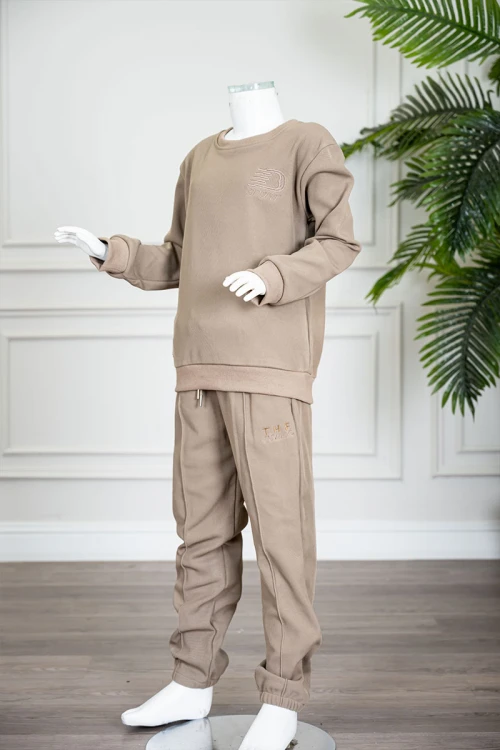 طقم قطعتين ولادي شتوي لون بيج غامق مزين بكتابات من الأمام بلوزة ياقة دائرية بأكمام طويلة و بنطلون طويل برباط في الخصر