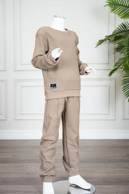 طقم قطعتين ولادي شتوي لون بيج غامق مزين بكتابات من الأمام بلوزة ياقة دائرية بأكمام طويلة و بنطلون طويل برباط في الخصر