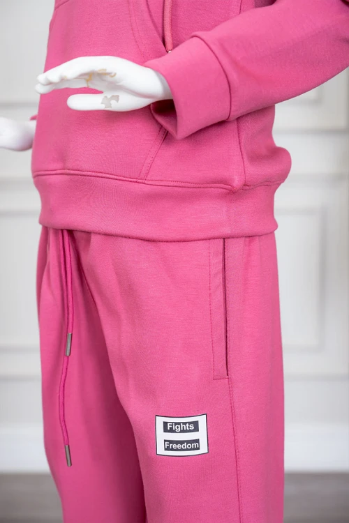 طقم بناتي شتوي قطعتين لون وردي هودي بقبعة متصلة برباط و بجيوب الكنغر و أكمام طويلة مزين بكتابات من الأمام  مع بنطلون طويل برباط في الخصر و جيوب من الجانبين