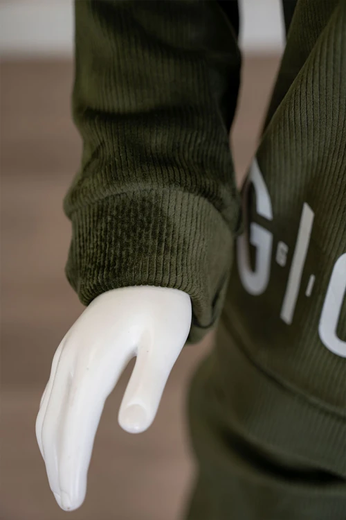 طقم بناتي شتوي قطعتين لون زيتي هودي بقبعة متصلة برباط و أكمام طويلة مزين بكتابات باللون الأبيض مع بنطلون طويل برباط في الخصر و جيوب من الجانبين