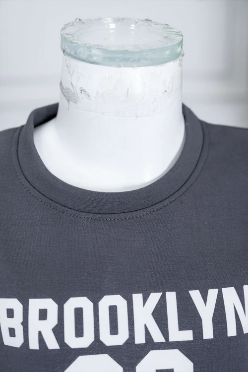 طقم بناتي شتوي قطعتين لون رصاصي بلوزة بياقة دائرية مزين بكتابات و خطوط باللون الأبيض بأكمام طويلة مع بنطلون طويل برباط في الخصر و جيوب من الجانبين