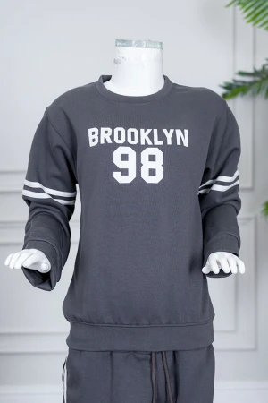 طقم بناتي شتوي قطعتين لون رصاصي بلوزة بياقة دائرية مزين بكتابات و خطوط باللون الأبيض بأكمام طويلة مع بنطلون طويل برباط في الخصر و جيوب من الجانبين 