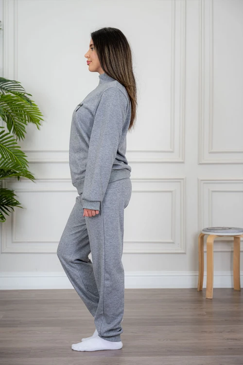 بيجاما نسائية قطعتين لون رمادي مزينة بكتابات من الأمام ياقة عالية بسحاب و بأكمام طويلة مع بنطلون طويل برباط في الخصر