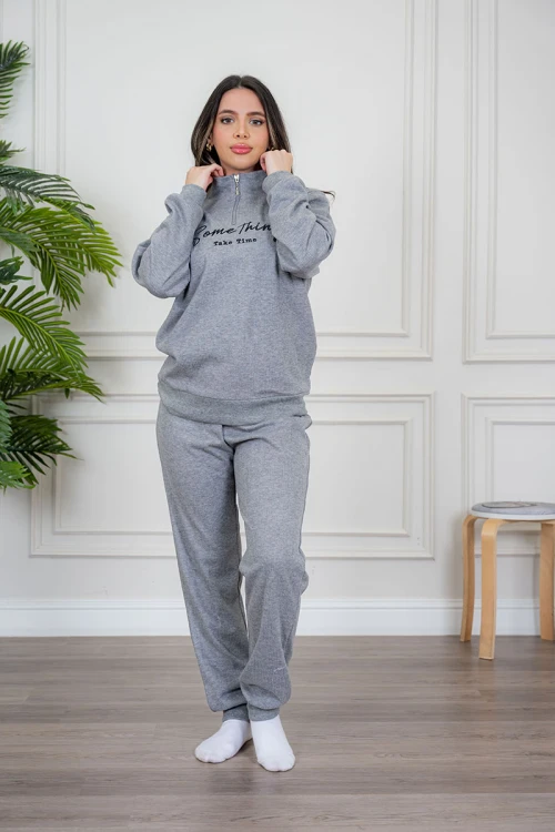 بيجاما نسائية قطعتين لون رمادي مزينة بكتابات من الأمام ياقة عالية بسحاب و بأكمام طويلة مع بنطلون طويل برباط في الخصر