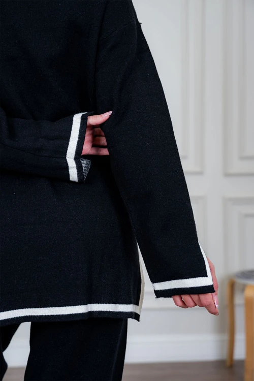 طقم تريكو نسائي شتوي قطعتين لون أسود مزين من الأطراف باللون الأبيض ياقة عالية مع بنطلون طويل