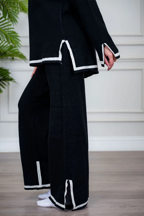 طقم تريكو نسائي شتوي قطعتين لون أسود مزين من الأطراف باللون الأبيض ياقة عالية مع بنطلون طويل