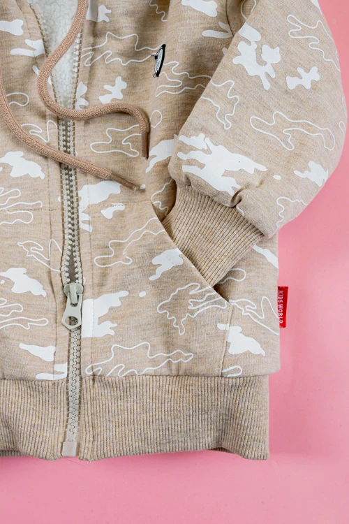 بلوفر أطفال شتوي مبطن لون بيج مزين برسومات باللون الأبيض قبعة متصلة برباط و بسحاب و جيوب من الأمام و أكمام طويلة