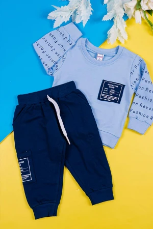 طقم قطعتين ولادي بلوزة لون سماوي مزينة بكتابات من الأمام و الخلف و بأكمام طويلة مع بنطلون كحلي طويل برباط في الخصر و زم في الأطراف