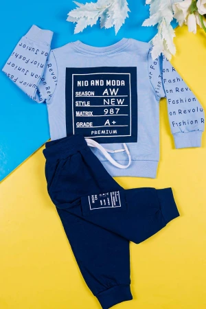 طقم قطعتين ولادي بلوزة لون سماوي مزينة بكتابات من الأمام و الخلف و بأكمام طويلة مع بنطلون كحلي طويل برباط في الخصر و زم في الأطراف