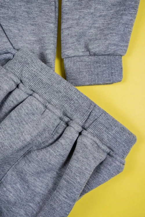 طقم قطعتين ولادي لون رمادي بلوزة بياقة عالية و بسحاب مزينة بكتابات و بجيب الكنغر من الأمام و بأكمام طويلة مع بنطلون طويل برباط في الخصر و زم في الأطراف